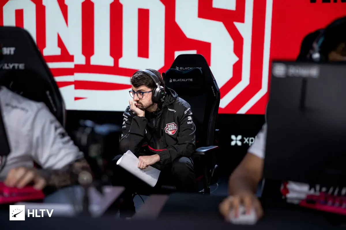 Gustavo Motta wearing a Red Canids jersey and headset, sitting in a gaming chair at a CS2 tournament.