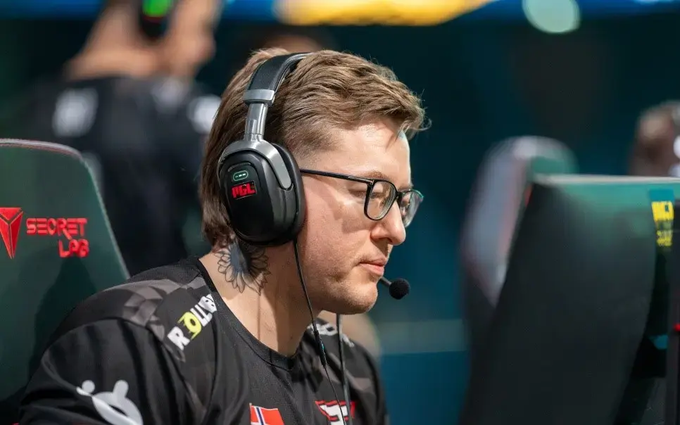 A focused esports player wearing headphones, playing at a tournament.