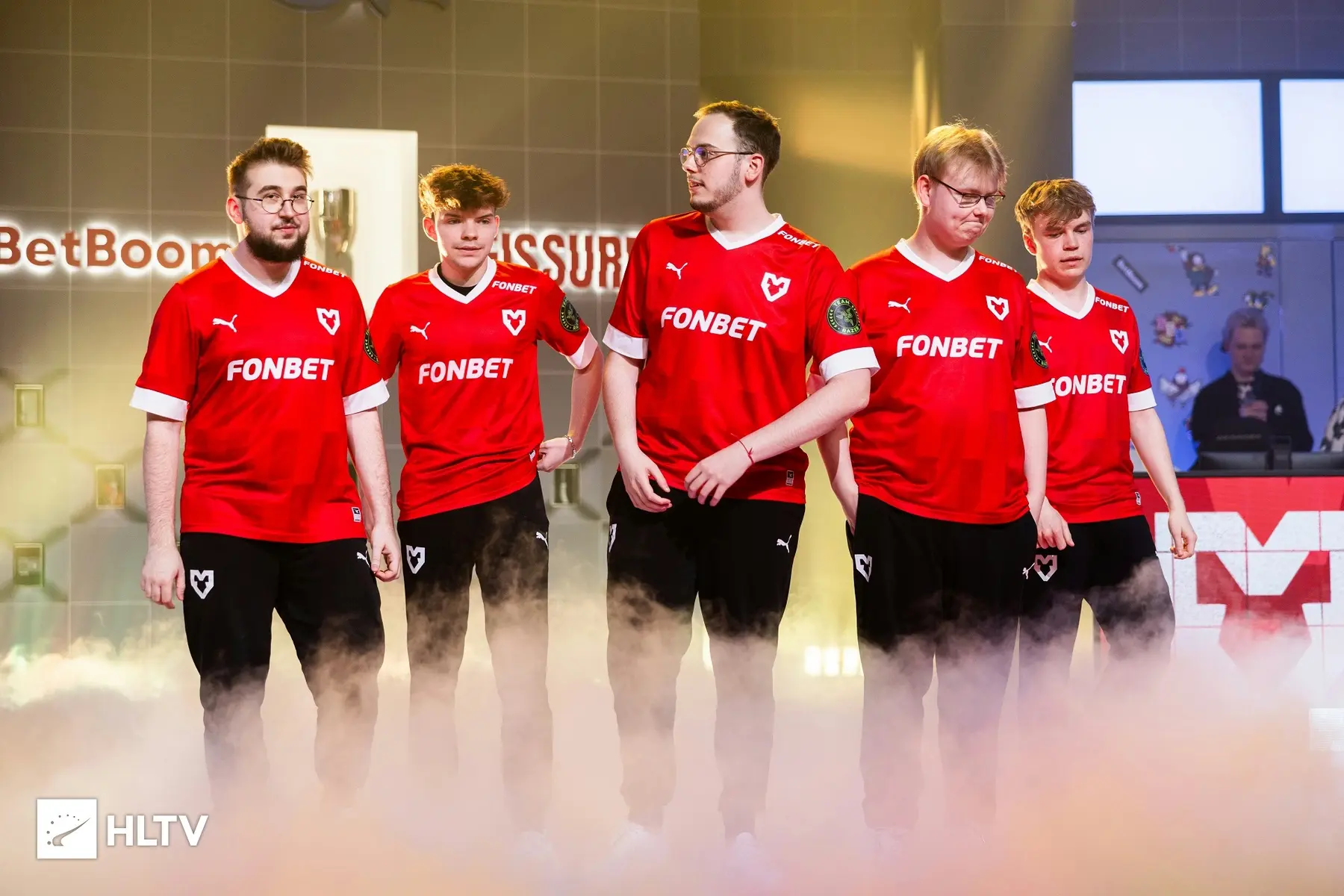 MOUZ CS:GO team posing in red jerseys with fog in the background.