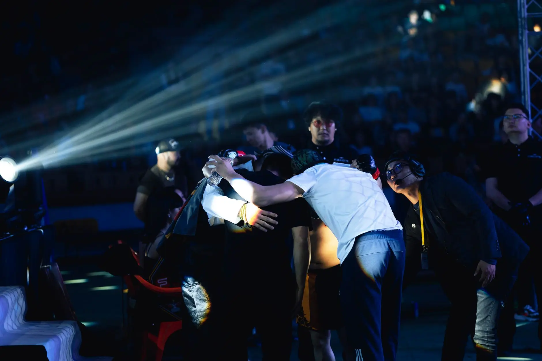 A group of people huddled together on stage with lighting effects.