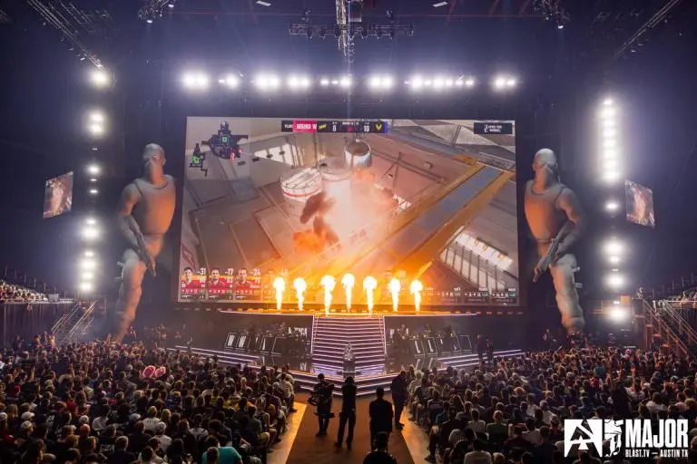 Wide shot of a BLAST.tv Major CS2 stage match in Austin with a massive screen and giant character statues