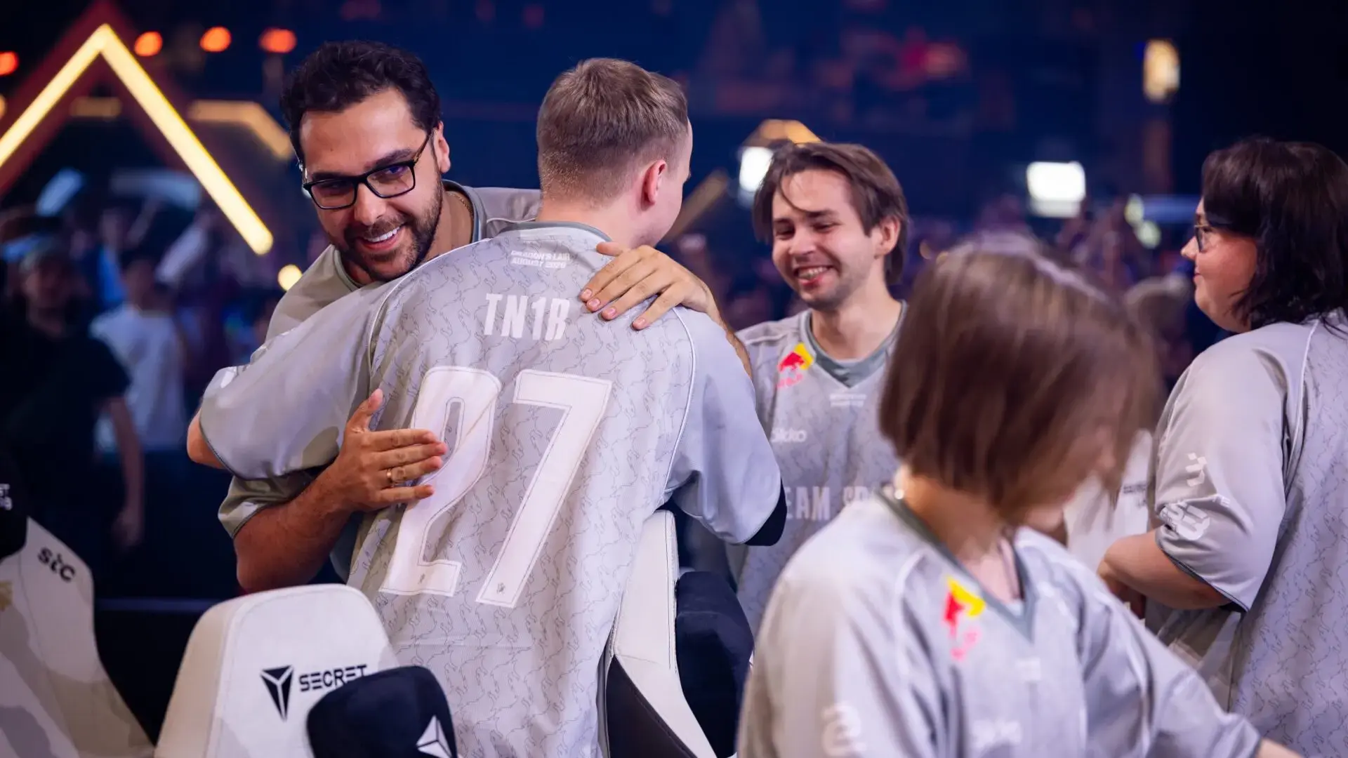 Tomaszin (TN1B) wearing a grey Team Spirit jersey being hugged by a coach at a CS2 esports event