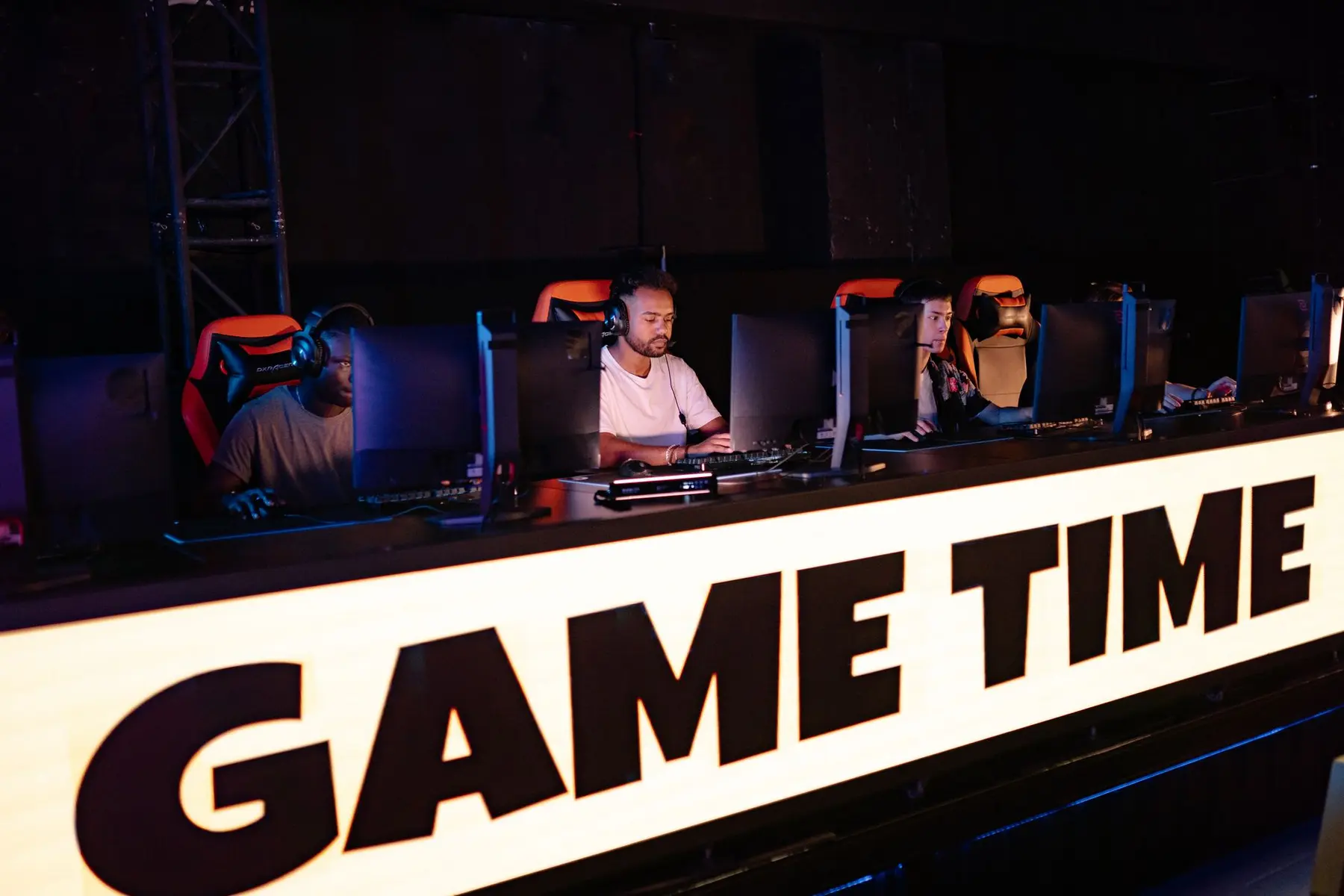 Professional gamers wearing headsets at a competition stage with a large 'GAME TIME' sign in the foreground